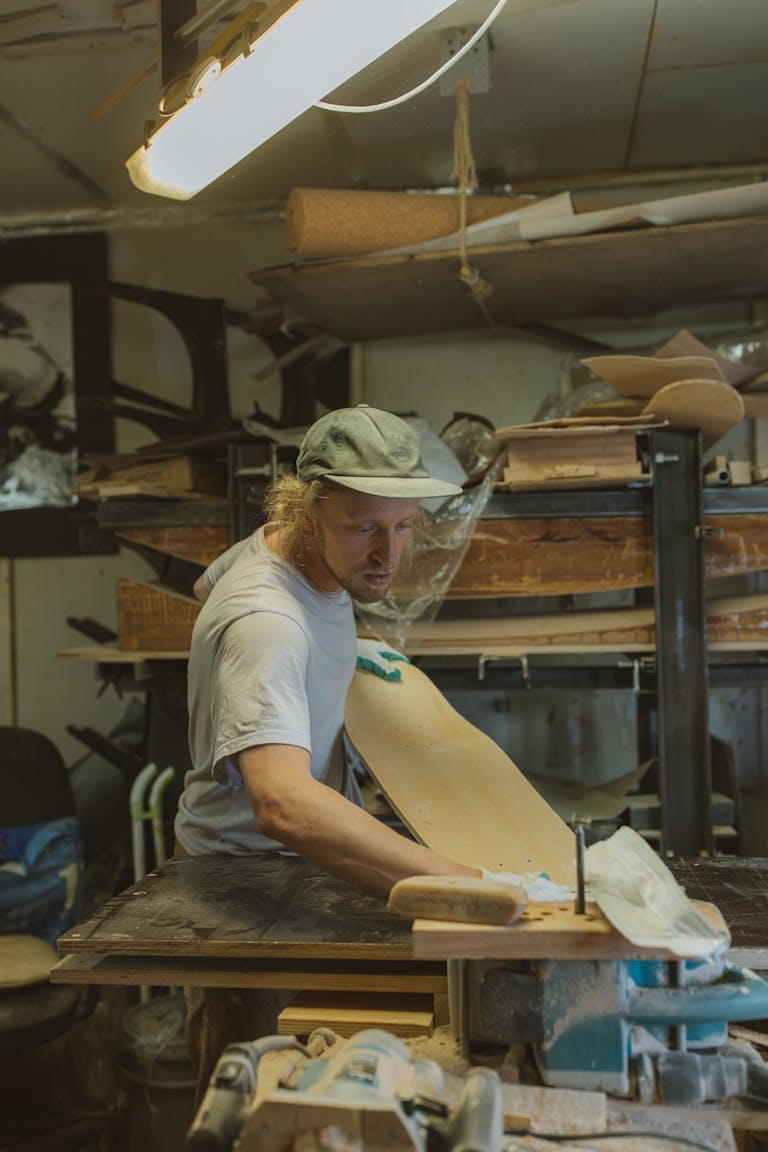 A skilled craftsman working on a skateboard design in a cluttered workshop.